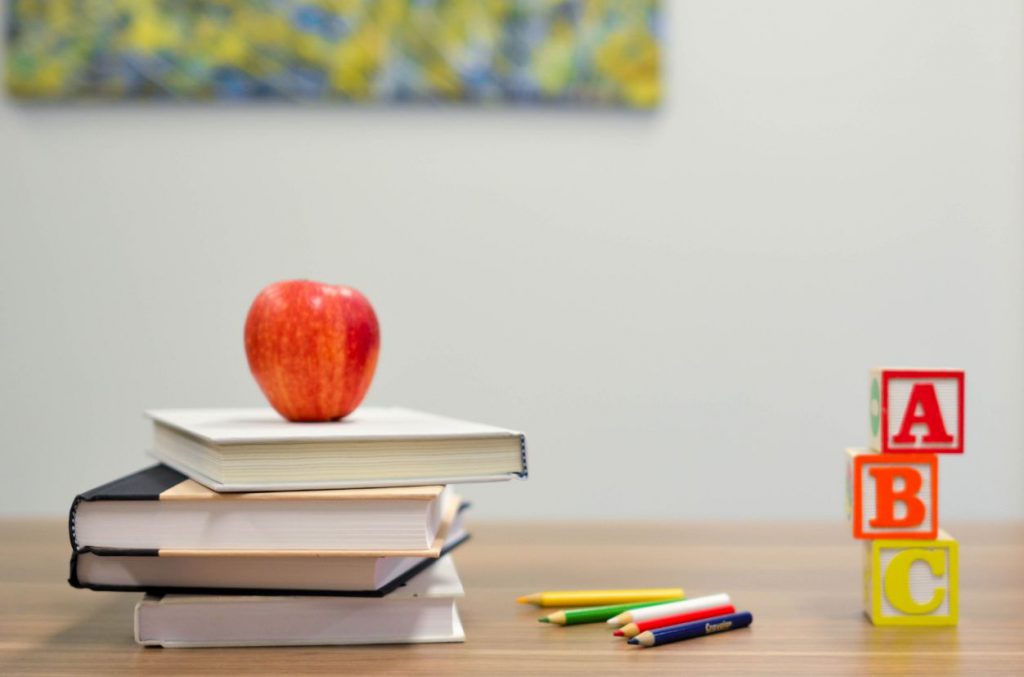 Image of school books and an apple on a teachers desk